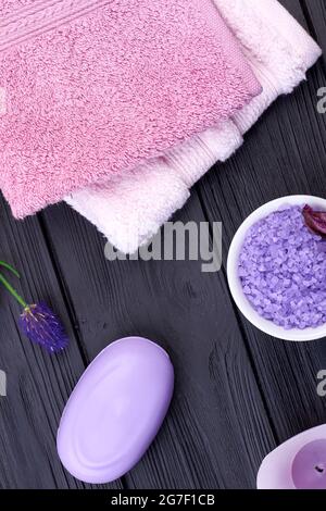 Terry towels with soap and sea salt on black wood. Stock Photo