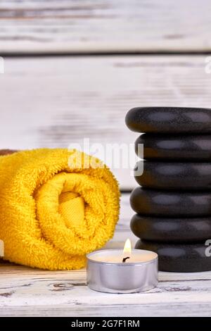 Vertical shot stack of stones with rolled towel and candle. Stock Photo
