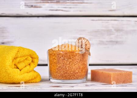 Glass of yellow salt with rolled towel and handmade soap. Stock Photo