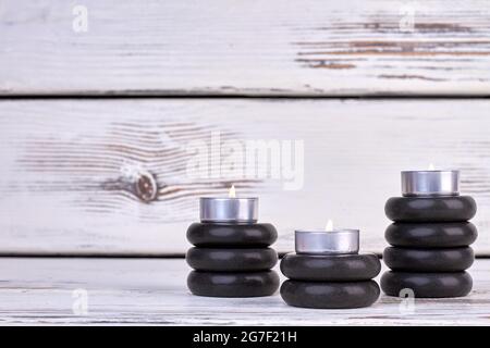 Stacks of black stones with burning candles still life. Stock Photo