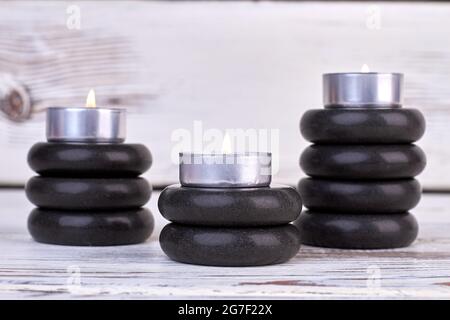 Stacks of black stones and burning candles still life. Stock Photo