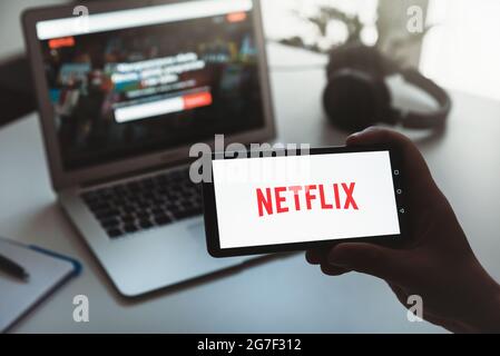 Wroclaw, Poland - JUN 17, 2021: Man with Netflix logo on screen. Netflix is most popular video streaming platform. Stock Photo
