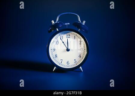 Analog clock front view, dark blue background Stock Photo