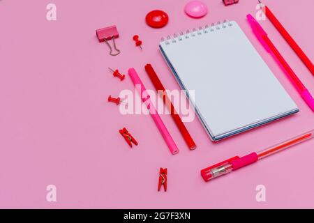 Stationery in pastel pink shades. On a pink background, flat lay. Markers and pencils with pens, spiral notebook top view. Copy space. Stock Photo