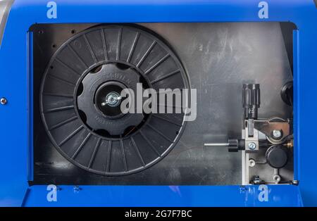 Side panel open on small MIG welder showing installed spool of welding filler wire Stock Photo