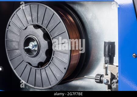 Side panel open on small MIG welder showing installed spool of welding filler wire Stock Photo