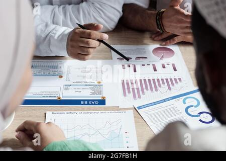 Group of financial specialists sitting at table and analyzing reports while making profit forecast Stock Photo