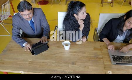 Corporate team of South Asians from India working sitting in front of a wooden table Stock Photo