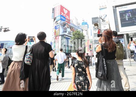 People take pictures of a giant digital 3D cat displayed on a 4K billboard in Tokyo's Shinjuku entertainment district, Japan on July 12, 2021. Credit: AFLO/Alamy Live News Stock Photo