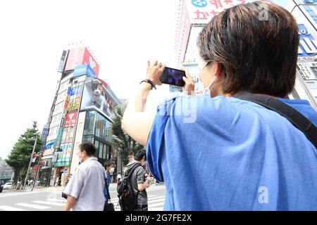 People take pictures of a giant digital 3D cat displayed on a 4K billboard in Tokyo's Shinjuku entertainment district, Japan on July 12, 2021. Credit: AFLO/Alamy Live News Stock Photo