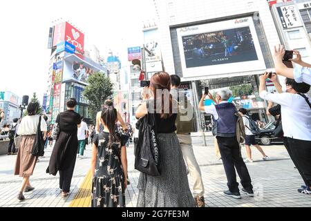 People take pictures of a giant digital 3D cat displayed on a 4K billboard in Tokyo's Shinjuku entertainment district, Japan on July 12, 2021. Credit: AFLO/Alamy Live News Stock Photo