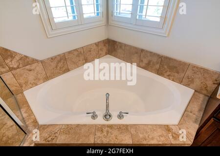Close up top view of a corner bathtub in a bathroom with ceramic tile surround Stock Photo