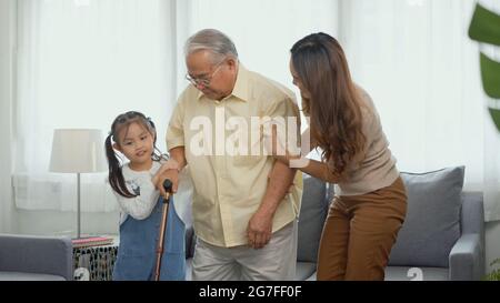 Asian family, Daughter and granddaughter take care support grandfather who is suffering from knee pain Got walking outside to take a walk And grandpa Stock Photo