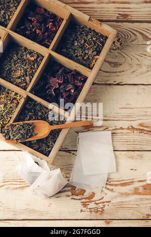 Tea bags and box with dry leaves on light wooden background Stock Photo