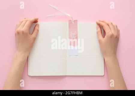 Woman with notebook and bookmark on color background Stock Photo