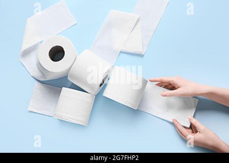 Female hands with rolls of toilet paper on color background Stock Photo