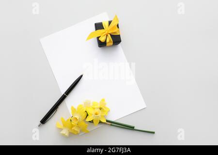 Beautiful daffodils, pen and blank paper sheet on white background Stock Photo