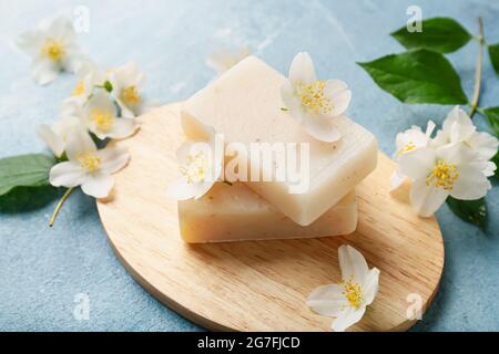 Board with soap bars and jasmine flowers on color background Stock Photo