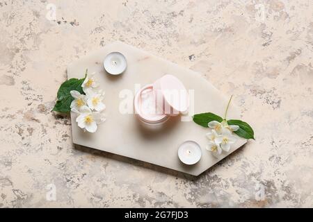 Composition with jar of cream, burning candles and jasmine flowers on grunge background Stock Photo