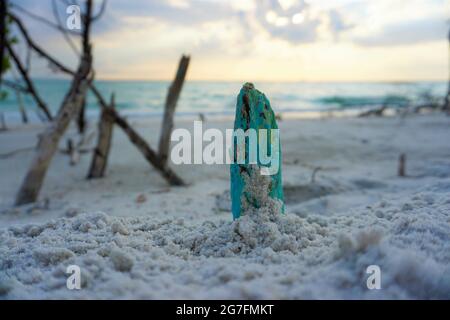 Selective focus shot of blue painted tree stump on white sand Stock Photo