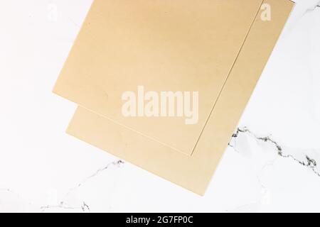 Beige A4 papers on white marble background as office stationery flatlay, luxury branding flat lay and brand identity design for mockup Stock Photo