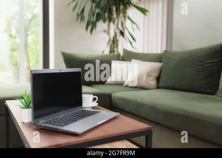 Work from home, workspace, desktop, remote work concept, gray thin laptop computer black empty screen on brown wooden table with white cup of coffee, Stock Photo