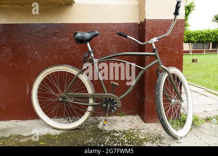 Old bicycle leaning on exterior wall. Stock Photo