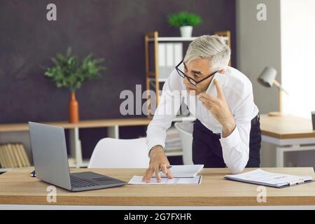 Businessman talking on cellphone in contemporary office. Stock Photo