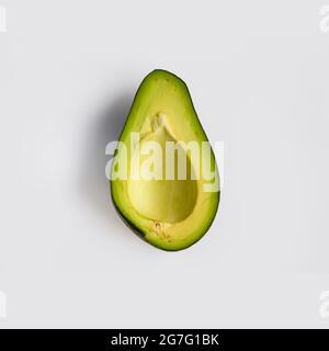 Half a pitted green ripe avocado isolated on light-gray background. Flat lay, top view Stock Photo