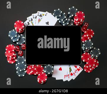 Casino chips, playing cards, dices and tablet pc pad on dark reflective background Stock Photo