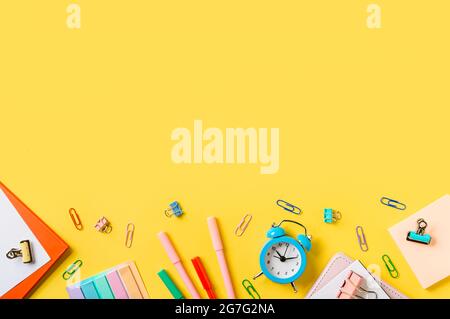 Education, back to school, freelancer work concept. School supplies, stationery accessories along bottom edge on yellow background. Flat lay, top view. Copy space Stock Photo