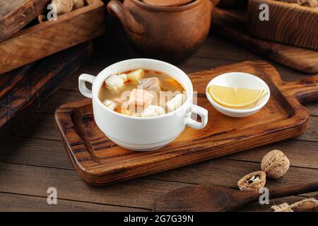 Ukha fish soup with lemon on the wooden table Stock Photo