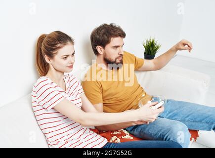 young couple sitting next to popcorn watching tv rest Stock Photo