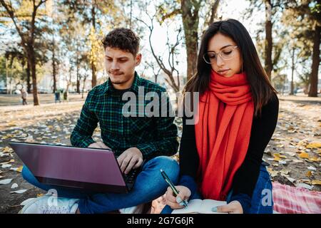 young couple using laptop to work outdoors Stock Photo