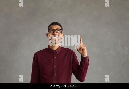 African american young man looking and pointing finger at empty space on gray background. Stock Photo
