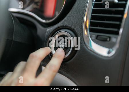 Male's finger pressing the start button, stop the engine in the luxury car. Stock Photo