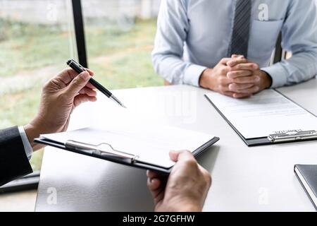 Senior committee manager reading a resume during a job interview, Employer interviewing to ask young male job seeker for recruitment talking in office Stock Photo