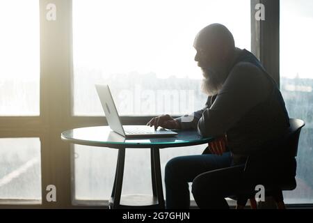 business man using laptop sitting near panoramic window . Stock Photo
