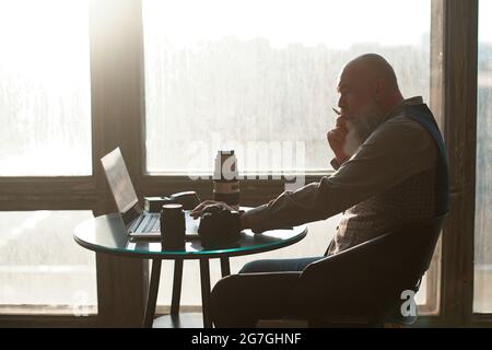 photographer is editing his photo while sitting at a table near the window. Stock Photo