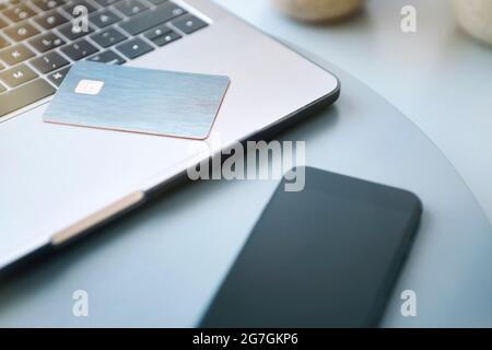 Laptop, electronic chip card and smartphone on blue round table. Paying online or client identification. Modern technology, wireless device and transf Stock Photo