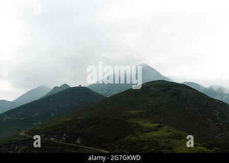 Thick gray clouds floating on sky over green hills on dull day in countryside Stock Photo