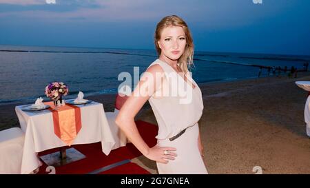 Eastern European Caucasian woman middle aged blonde hair light skin pale complexion in formal attire at night Posing on the red carpet and sand Stock Photo