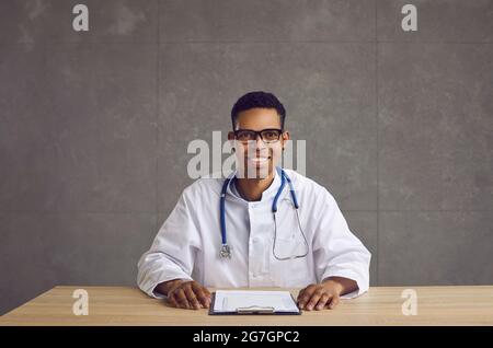Portrait of a friendly young african american male healthcare worker on gray concrete background. Stock Photo