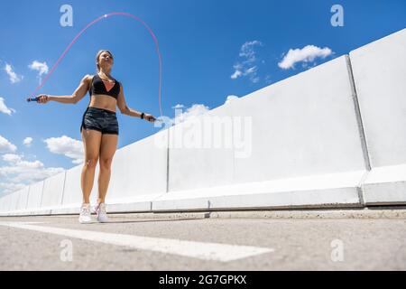 Young Woman training with the outdoor skipping rope , side view Stock Photo