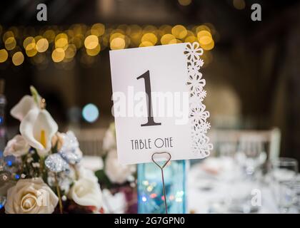 Table One 1 wedding breakfast beautiful light with out of focus fairly lights in background. Flowers and wedding table ornaments. Stunning decorations Stock Photo