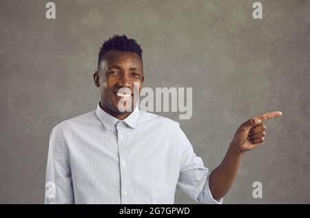 Portrait of happy handsome young black man smiling and pointing away with his finger Stock Photo