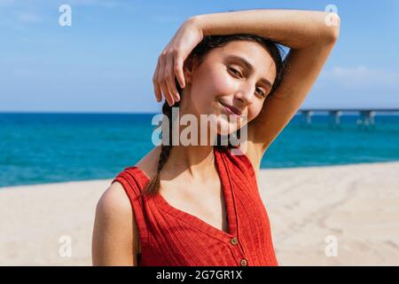 Young female in white shirt watering fresh potted Monstera deliciosa plant at home Stock Photo