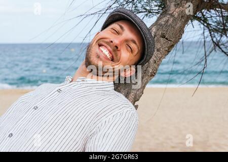From bellow young African American female in trendy outfit and glasses looking away while leaning against colorful wall on a sunny day Stock Photo