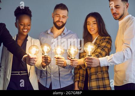 Diverse multinational group of people hold lightbulb together studio shot Stock Photo