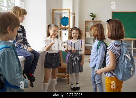 Elementary schoolchildren group talking during break standing in classroom Stock Photo